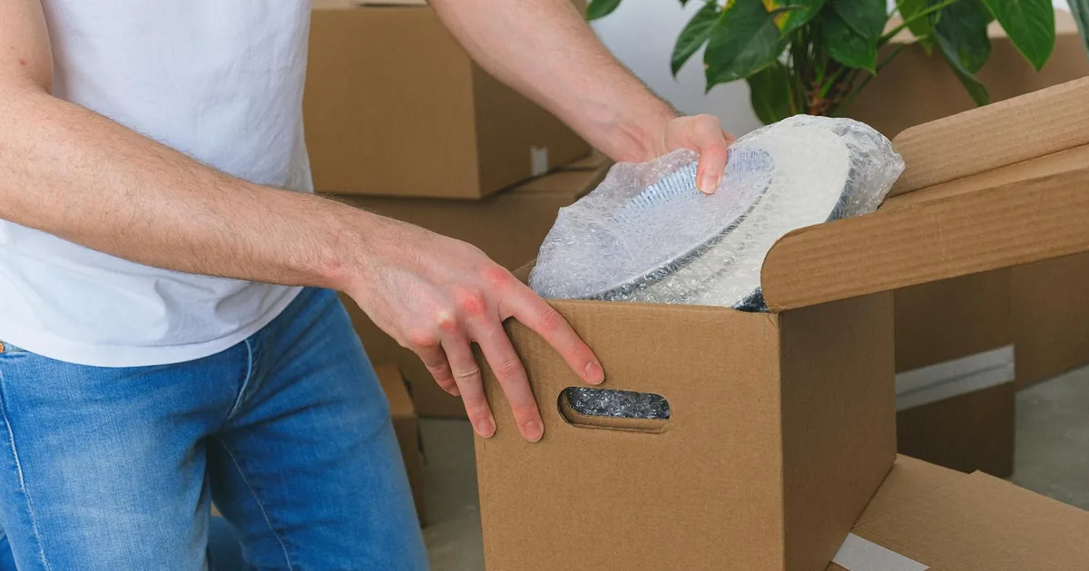 Courier packing a corrugated box for international shipping from Hyderabad with bubble wrap and tape